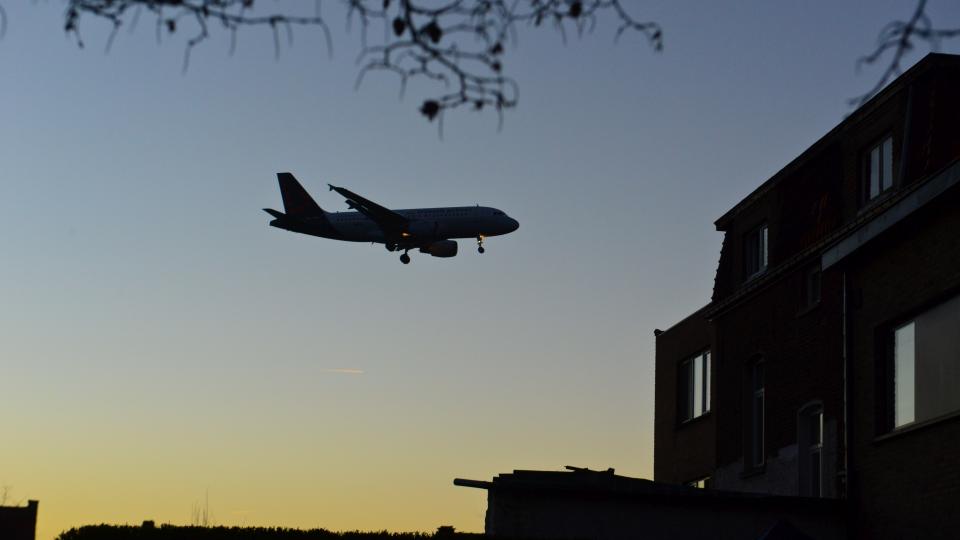 Ein Flugzeug am Nachthimmel hinter einem Wohngebäude.