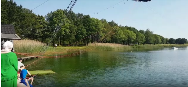 Ein See mit einer Wasserskianlage. Eine Person bereitet sich gerade auf den Start vor.