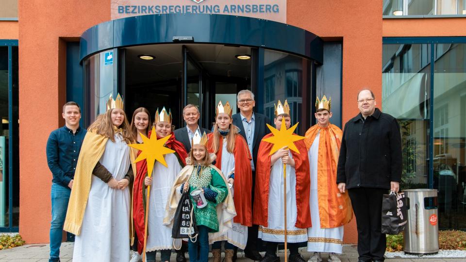 Die Sternsinger*innen der Arnsberger Propsteigemeinde mit Regierungspräsident Hans-Josef Vogel (hinten Mitte rechts) und Regierungsvizepräsident Volker Milk (hinten Mitte links)