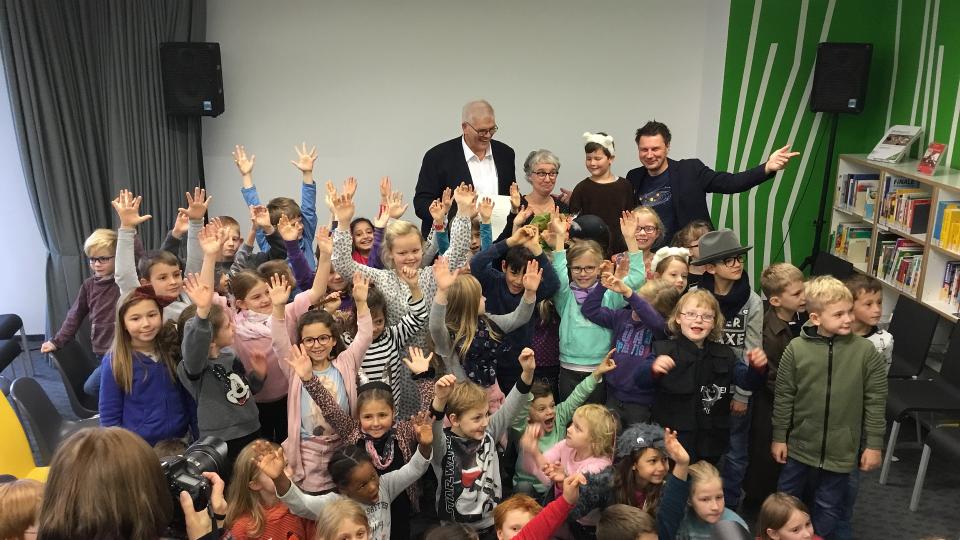 (hinten v.l.n.r.) Regierungspräsident Hans-Josef Vogel, Illustratorin Katja Gehrmann und André Gatzke, Moderator der „Sendung mit der Maus“ umringt von zahlreichen Kindern