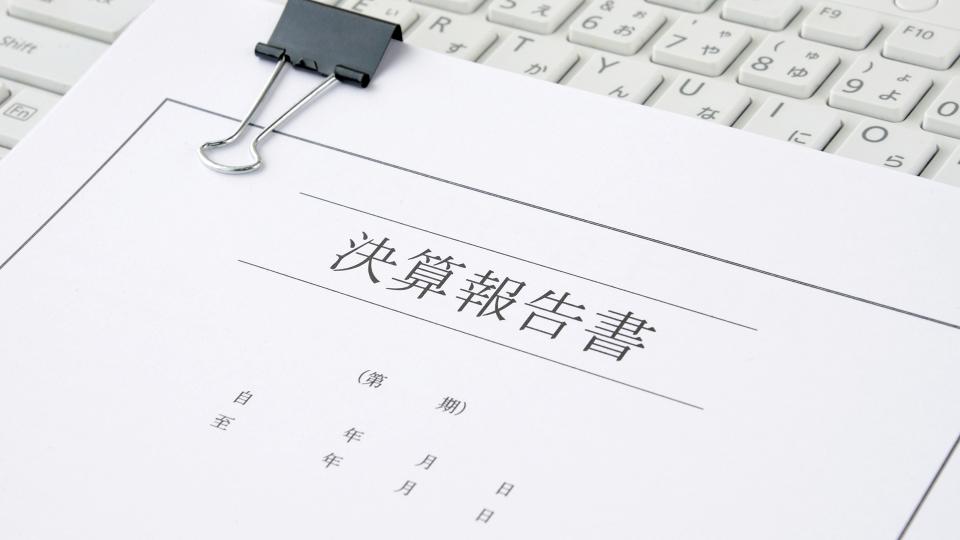 Ein zusammengeheftetes Schriftstück mit aufgedruckten ostasiatischen Zeichen liegt auf einer Tastatur. 