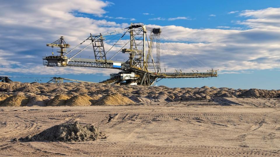 Abgebildet ist ein riesiger Schaufelradbagger in karger Landschaft. 