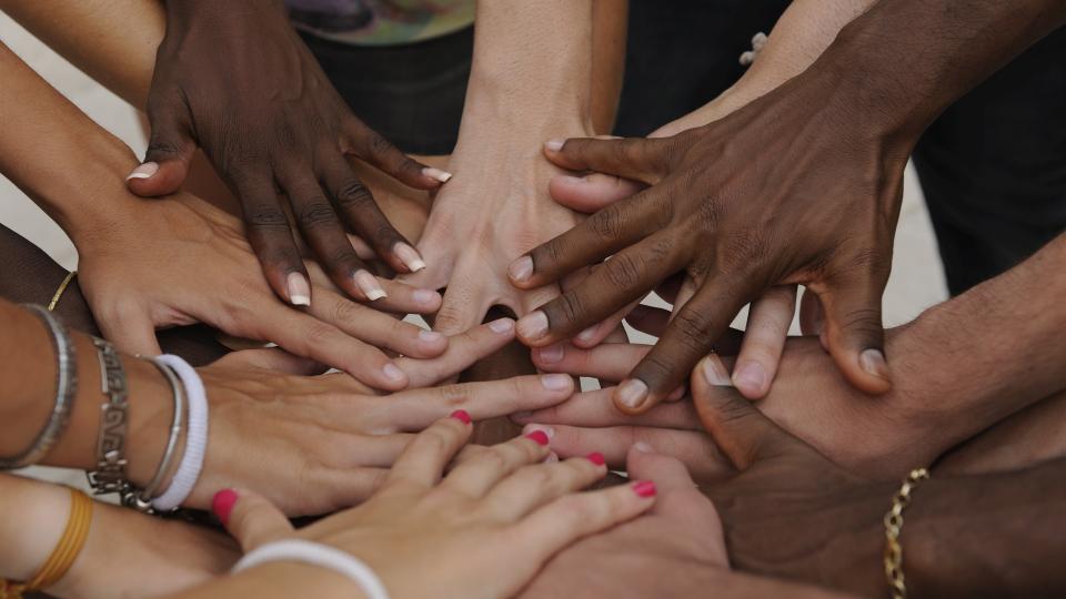 Sich berührende Hände von Menschen unterschiedlicher ethnischer Herkunft.