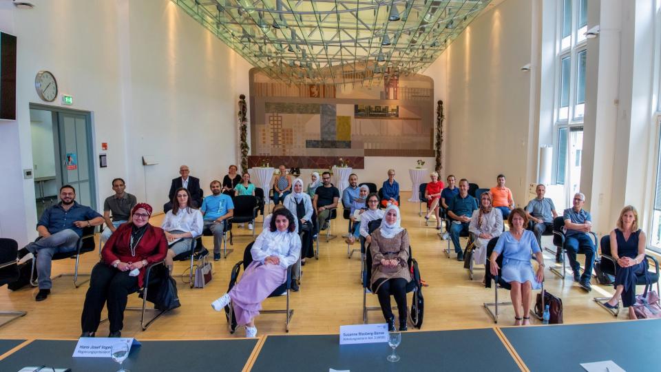 Die Gruppe der 23 neu eingestellten Lehrkräfte mit Fluchthintergrund bei der Übergabe der Anstellungsverträge mit Regierungspräsident Hans Josef Vogel (hinten links) und Susanne Blasberg-Bense vom Ministerium für Schule und Bildung (hinten rechts)