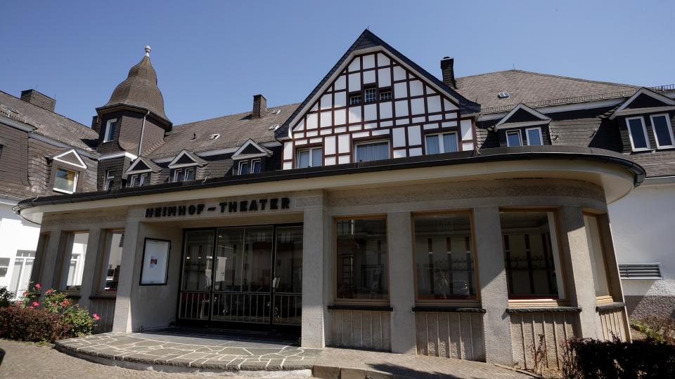 Bild eines Theaters in einem schiefergedeckten Gebäude, teilweise mit einer Fachwerkfassade und der Beschriftung: "Heimhof-Theater".