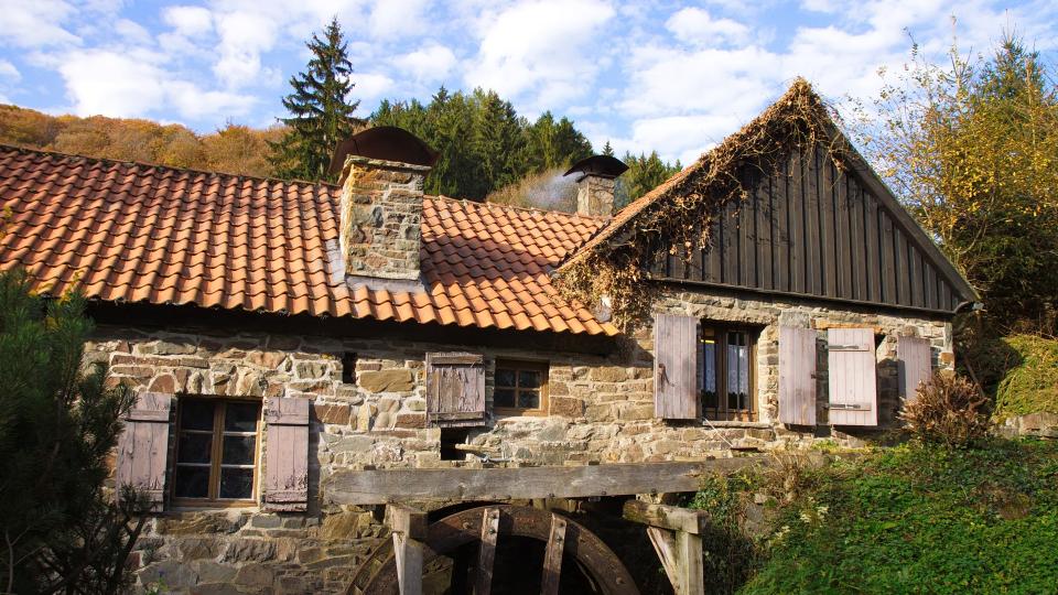 Bild einer idyllisch gelegenen alten Wassermühle.