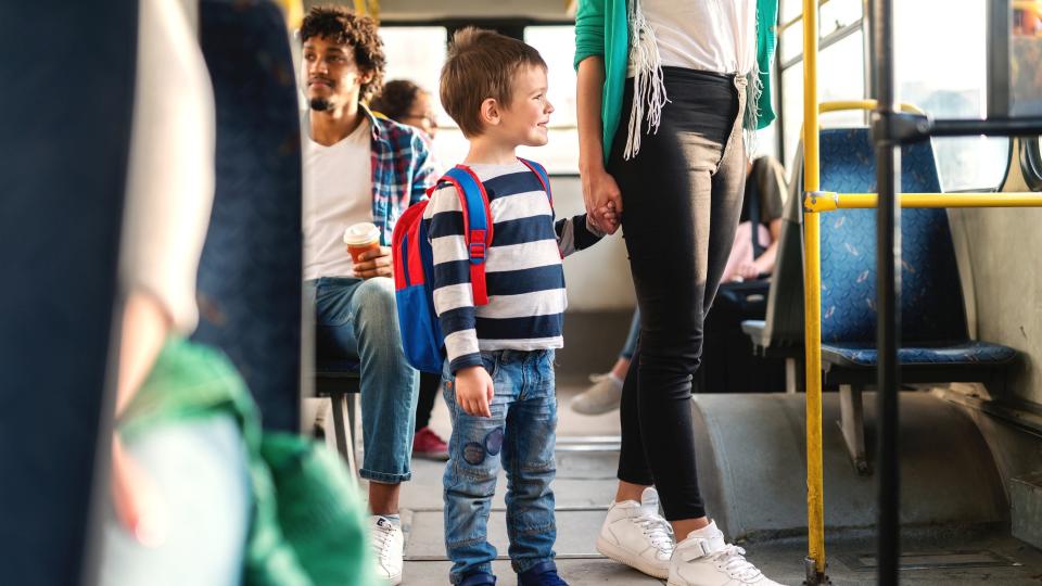 Ein kleiner Junge an der Hand seiner Mutter in einer Straßenbahn.