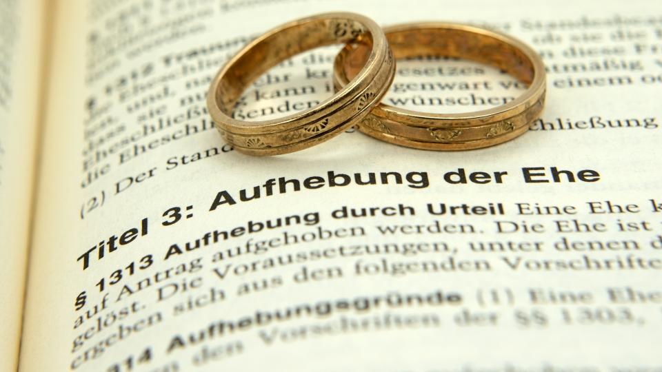 Zwei Eheringe auf einem Gesetzestext zur Eheaufhebung