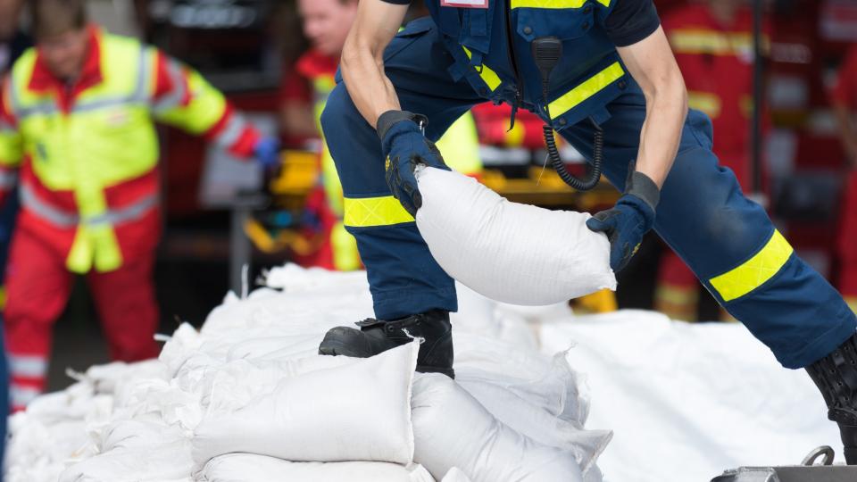 Helfer transportiert Sandsäcke