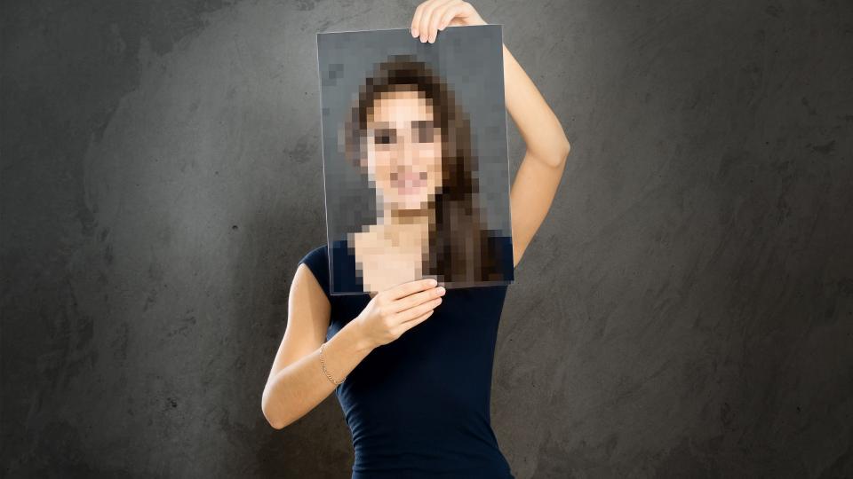 Eine junge Frau hält sich einen Rahmen vors Gesicht, das dieses verpixelt darstellt.