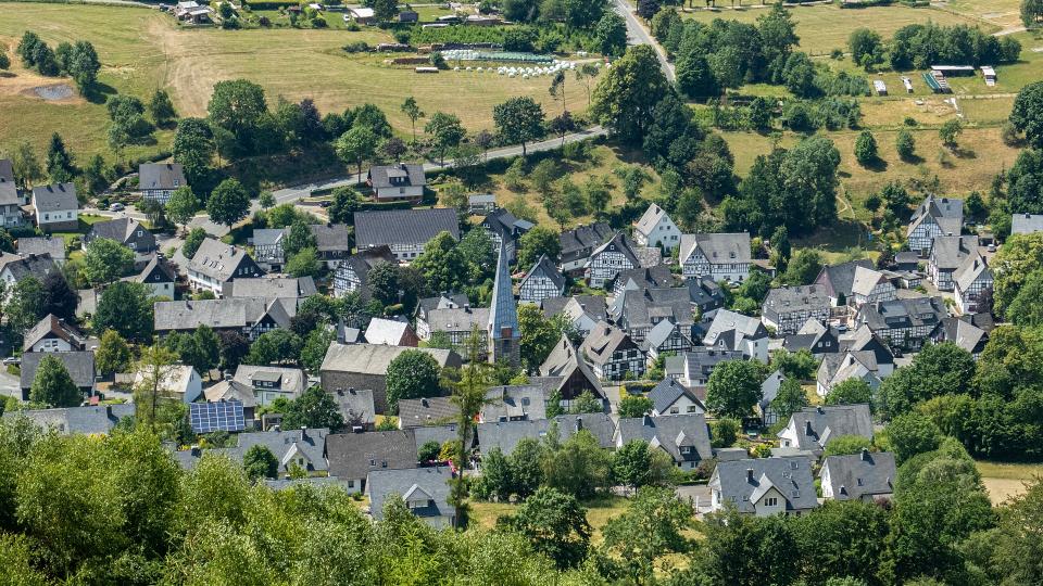 Abgebildet ist ein Dorf in ländlicher Umgebung. 