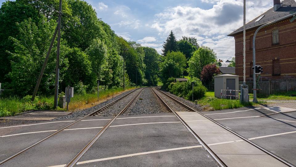 Abgebildet ist ein Bahnübergang in ländlicher Umgebung. 