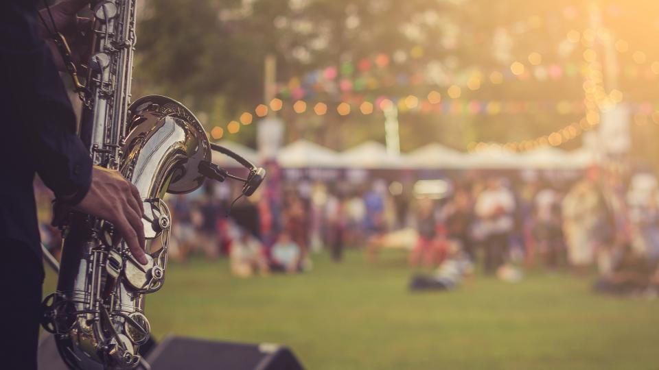 Ein Musiker spielt auf einem Konzert im Freien das Saxophon. 