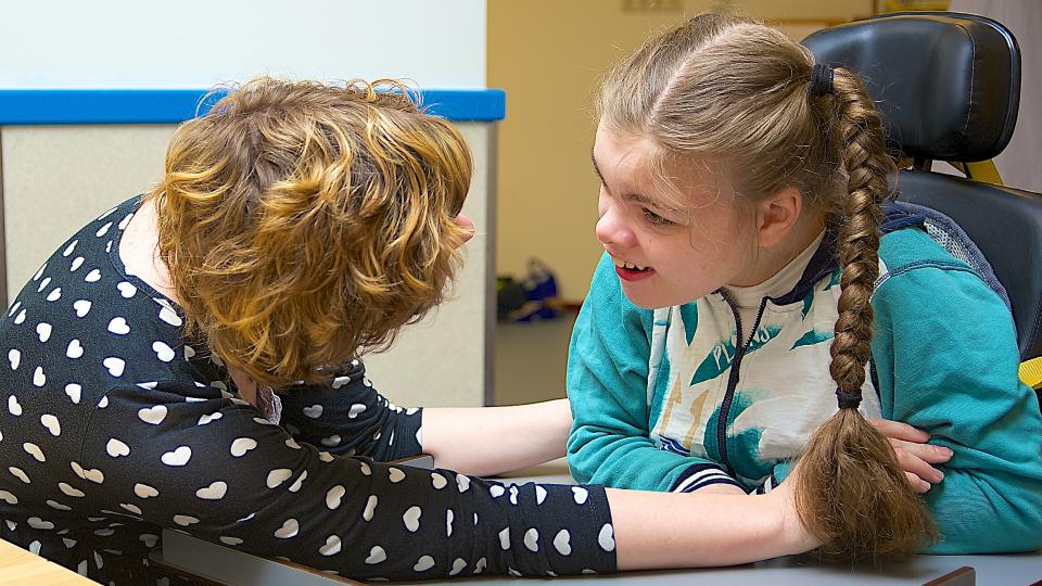 Eine Pflegerin kümmert sich um ein Mädchen mit Behinderung. 