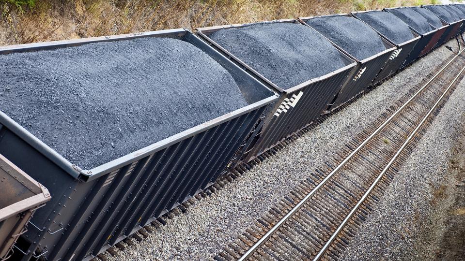 Ein Zug transportiert in sehr vielen Waggons Kohle. 