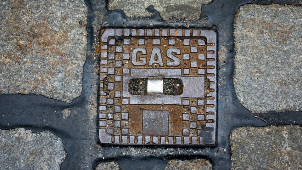 Abgebildet ist eine Nahaufnahme einer eckigen Straßenklappe mit der Aufschrift "Gas".