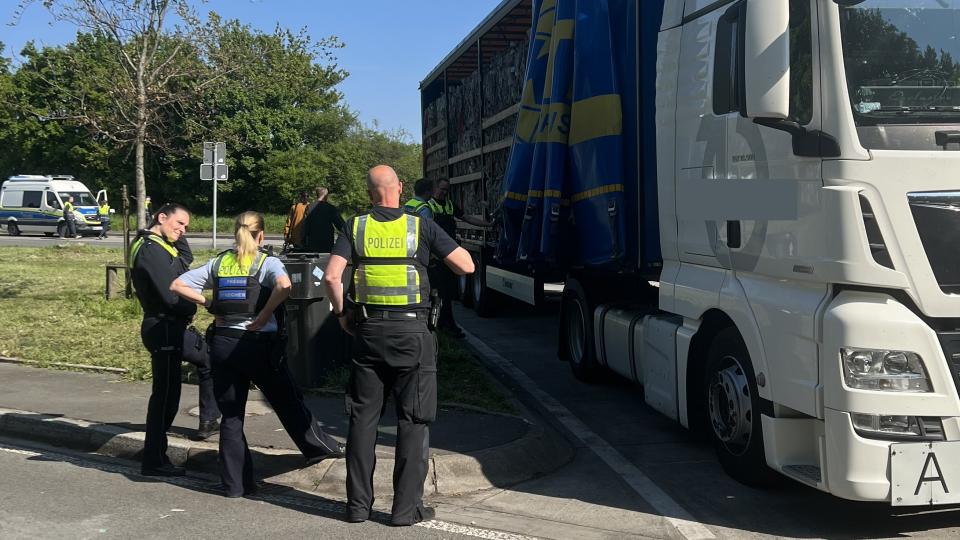 Das Bild zeigt einen Gruppe von Personen vor der Ladefläche eines LKW.