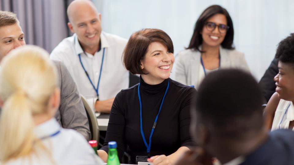 Das Bild zeigt eine diverse Gruppe von Personen in einer Konferenz.