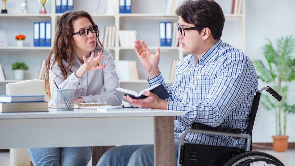 Ein im Rollstuhl sitzender Schüler lernt zusammen mit einer weiteren Schülerin für seine Prüfung.