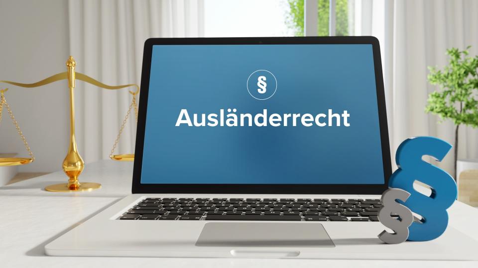 Ein aufgeklappter Laptop, auf dem Bildschirm steht Ausländerrecht. Im Hintergrund eine Waage und rechts zwei Paragraphenzeichen.