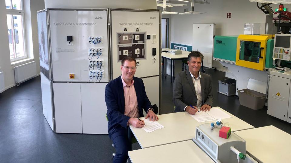 Herr Thorsten Holzhäuser vom Verein Technikförderung Südwestfalen und Herr Dirk Kolar, Fortbildungsdezernent der Bezirksregierung Arnsberg, sitzen zusammen in einem Labor an einem Tisch und unterzeichnen jeweils die Kooperationsvereinbarung zwischen dem Verein Technikförderung Südwestfalen und der Bezirksregierung.