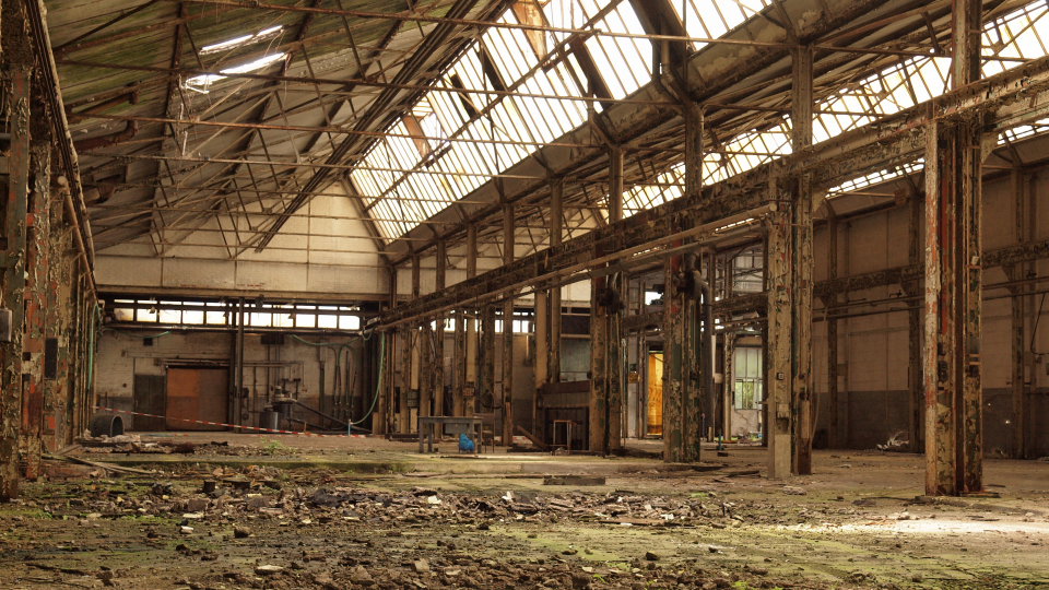 Abgebildet ist eine verlassene und heruntergekommene Firmenhalle. 