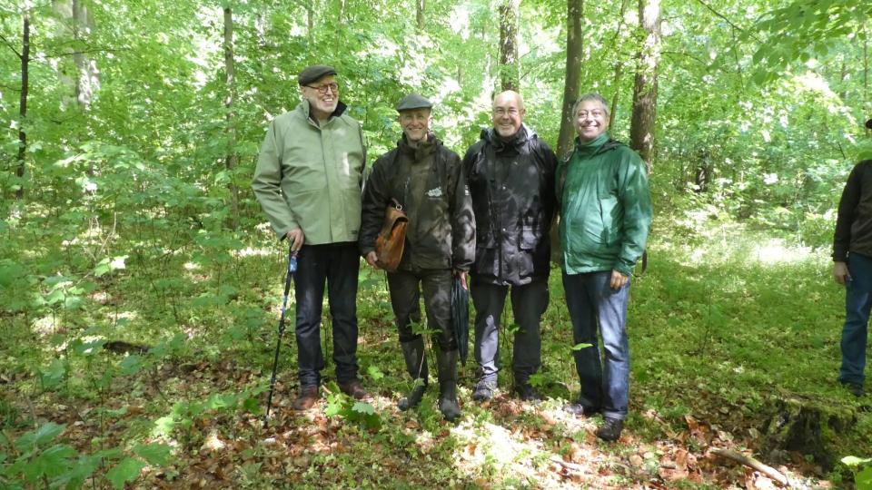 Eine Gruppe von vier Personen steht in einem Waldgebiet.