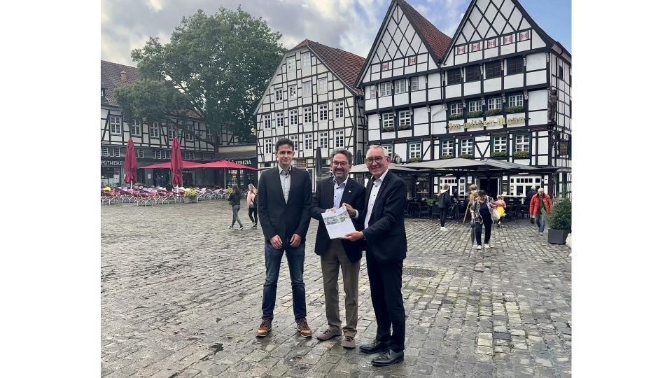 Regierungspräsident Heinrich Böckelühr übergibt zusammen mit Jan Peters (Dezernent Städtebauförderung der BR Arnsberg) den Förderbescheid an Bürgermeister Dr. Eckhard Ruthemeyer 