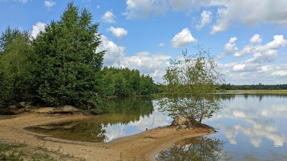 Abgebildet ist ein See, der sich in ländlicher Umgebung befindet. 