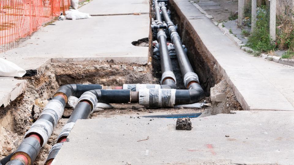 Reparatur und Umbau der Fernwärmeleitung parallel zur Straße mit Baustellenschutzzaun. 