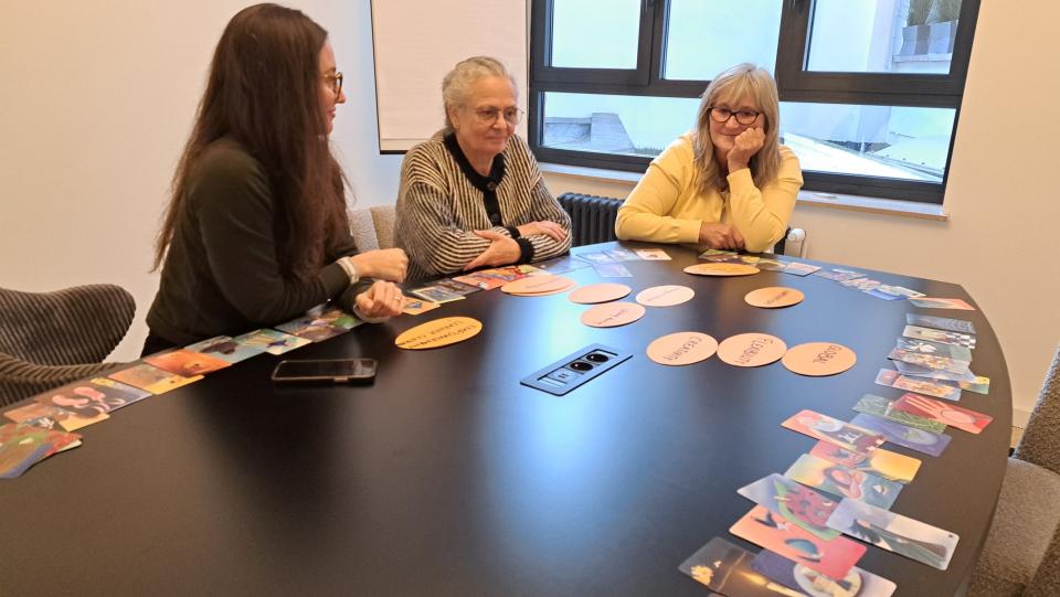 Drei Personen sitzen an einem Konferenztisch.