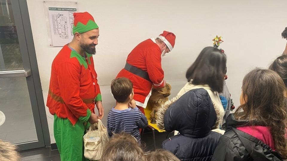 Der Nikolaus und ein Weihnachtself verteilen Geschenke