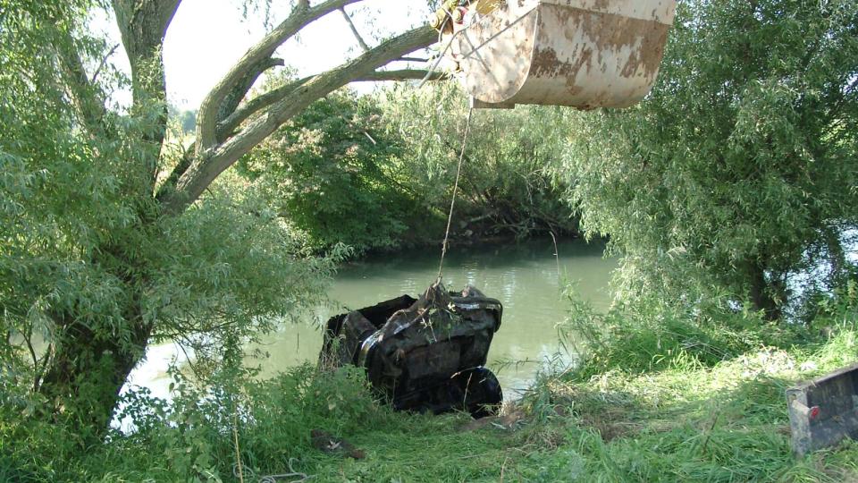 Ein Auto wird per Bagger aus dem Fluss gezogen.