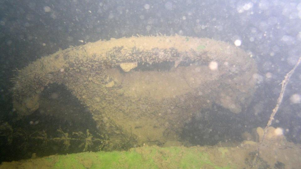 Ein mit Algen bewachsenes Lenkrad unter Wasser.