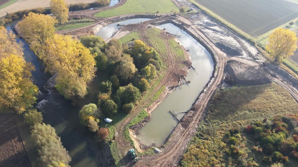 Lufaufnahme der Baustelle mit vielen Baumstämmen am Flussufer