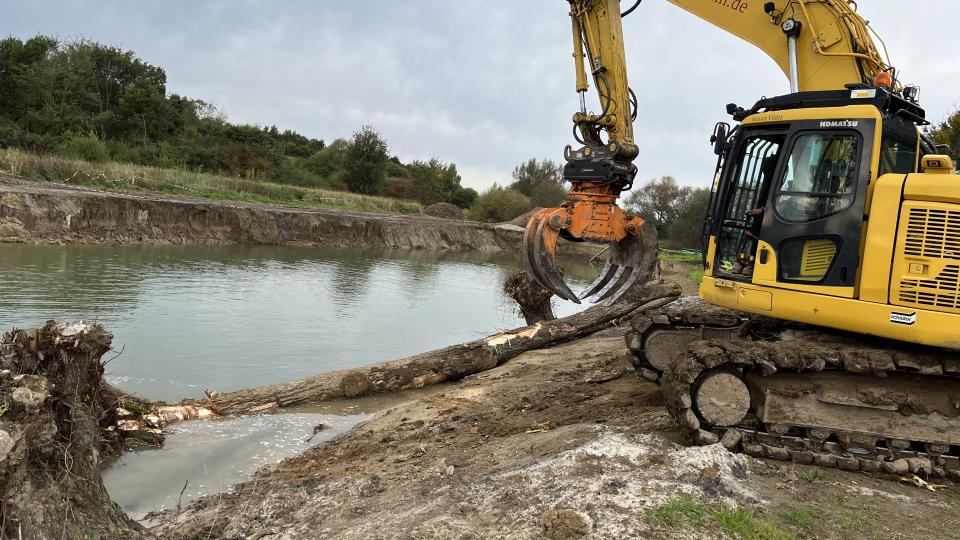 Ein Bagger arbeitet am Flussufer