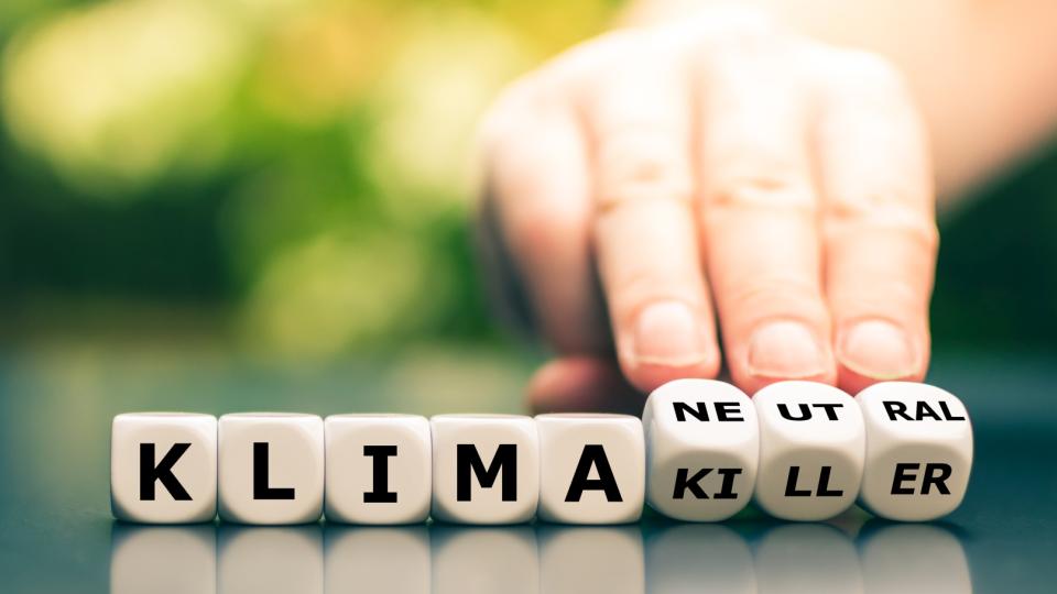 Eine Hand dreht Würfel und ändert den Ausdruck "Klimakiller" in "Klimaneutral".