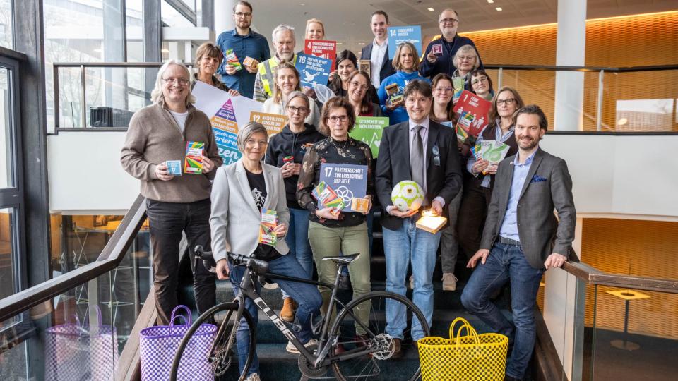 Abgebildet sind mehrere Personen, die für ein Bild posieren. Im Vordergrund ist ein Fahrrad abgestellt.