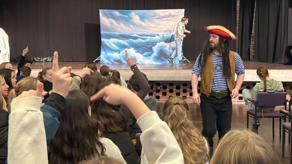 Abgebildet ist eine Theateraufführung in einer Schulaula. 