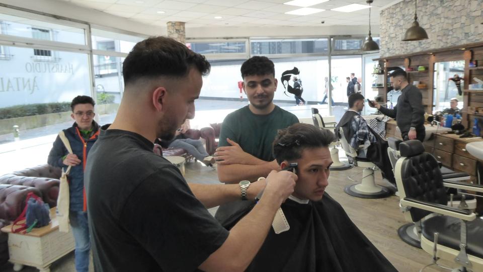 Abgebildet ist ein Friseur bei der Arbeit im Friseursalon.