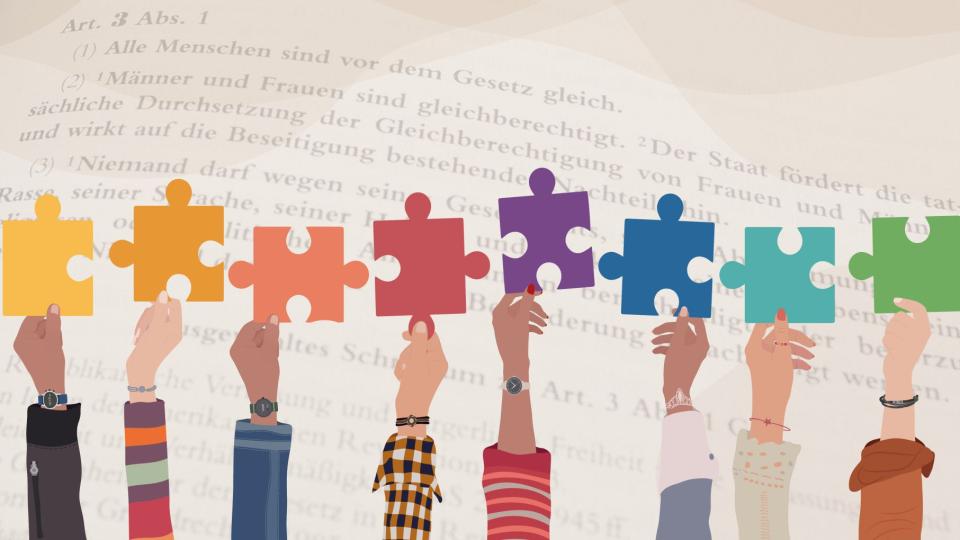 Abgebildet sind Puzzlestücke in verschiedenen Farben, die nebeneinander hochgehalten werden. Im Hintergrund ist der Inhalt von Artikel 3 Absatz 1 Grundgesetz abgebildet.