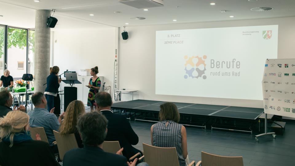 Abgebildet sind Impressionen zur Preisverleihung im internationalen Logowettbewerb „Berufe rund ums Rad“.