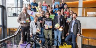 Abgebildet sind mehrere Personen, die für ein Bild posieren. Im Vordergrund ist ein Fahrrad abgestellt.