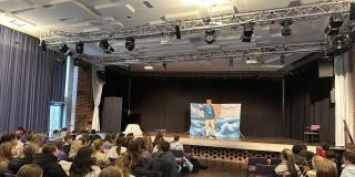 Abgebildet ist eine Theateraufführung in einer Schulaula. 