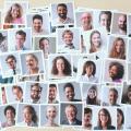 An einer Pinnwand aufgehängte Polaroid Bilder von lachenden Menschen unterschiedlicher ethnischer Herkunft. 