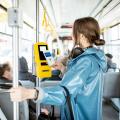Eine Frau bezahlt kontaktlos mit ihrem Smartphone in einer Straßenbahn.