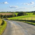 Bild einer kurvenreichen Landstraße zwischen landwirtschaftlich genutzen Feldern.