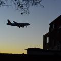 Ein Flugzeug am Nachthimmel hinter einem Wohngebäude.