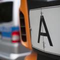 Das Bild zeigt ein Schild "A" an der Front eines LKW, im Hintergrund ist verschwommen ein Polizeiwagen zu sehen.