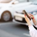 Nahaufnahme von Händen einer Frau mit Smartphone vor parkenden Autos.